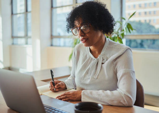 istock A mature business woman looking at her laptop computer and writing down notes with copy space. Stock photo 1498066019