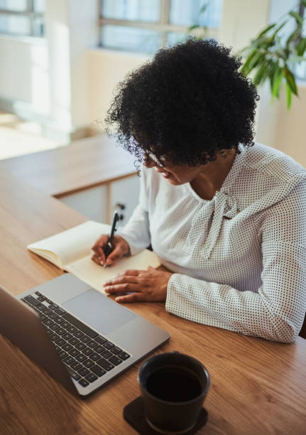 istock A business woman at her desk looking down while taking down notes from her laptop computer. Stock photo 1498066059
