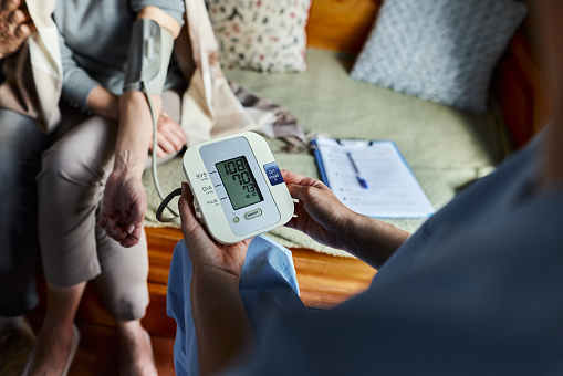 Close up of unrecognizable doctor measuring blood pressure of a patient during a home visit.