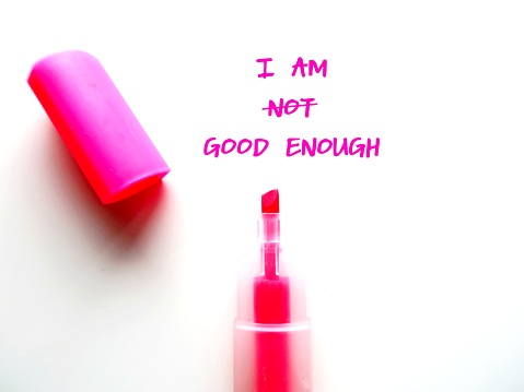 Pink highlight pen with text written on white paper I AM NOT GOOD ENOUGH, changed to I AM GOOD ENOUGH, concept of overcome negative inner voice and change to positive self talk to boost self esteem
