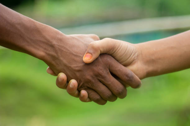 istock A white man and a black man shake hands together with each other with their hands and the background behind them is blurred 1498074043