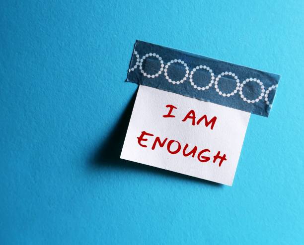 istock Stick note on blue copy space background with handwritten text I AM ENOUGH concept of self-acceptance, affirmation to tell yourself you are good enough and capable enough to become everything you want to be 1498074201