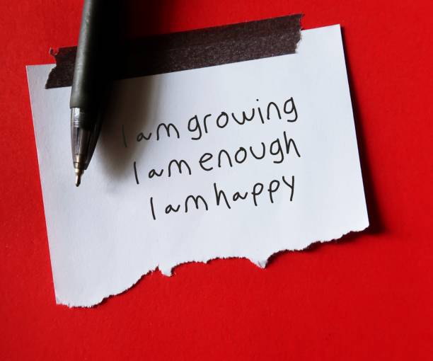 istock Note stick on red background with handwritten text I AM GROWING I AM ENOUGH I AM HAPPY - positive affirmations self talk practice for daily encouragement and boost self esteem - optimistic voice remind to look on the bright side 1498074233