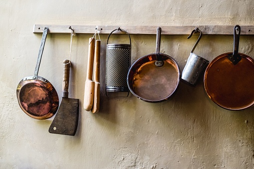 An assortment of cookware and kitchenware, including hanging on a wall in an organized manner