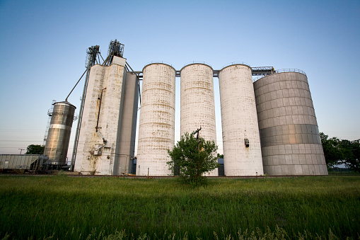 A set of grain elevators on a farm along Historic Route 66, in Illinois, USA. Shot at sunset, with a wide angle, and low perspective.