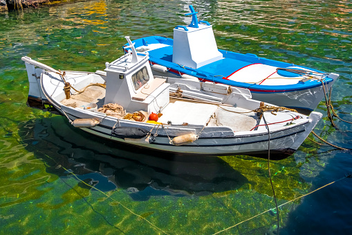 Two small greek wooden fishing boats in the harbour, Santorini Islands, Greece.