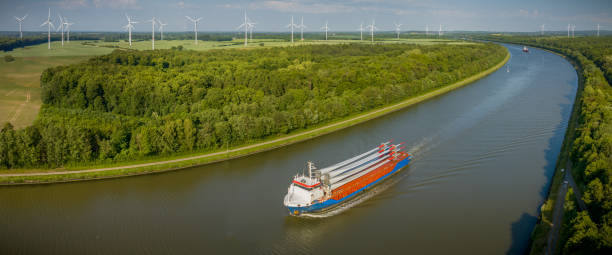 istock Cargo ship carrying wind turbine blades is navigating through the Kiel Canal with a wind farm in the background. Transportation of blades for wind turbines on a cargo ship. 1498080416
