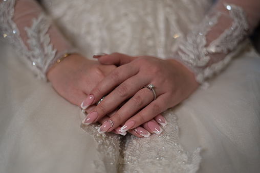 HANDS OF A BRIDE IN WHITE DRESS