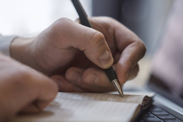 istock A man's hand inscribing in a notepad on a modern laptop, captured closely, with a vague background 1498083464