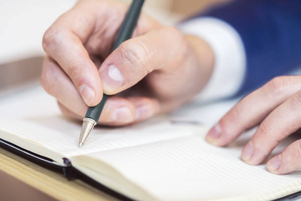 istock A man's hand inscribing in a notepad, captured closely, with a vague background 1498083497