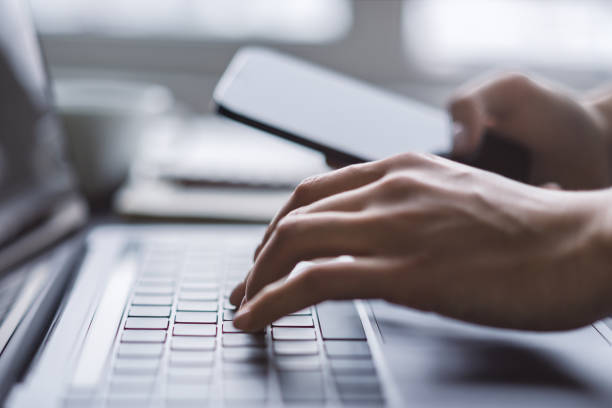 写真は、現代のラップトップのキーボードで入力する女性の手に焦点を当て、オフィスの設定がぼやけて見える - mail keyboard button ストックフォトと画像