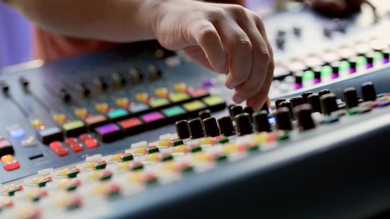 Close up to DJ hand controlling sound mixing board switches