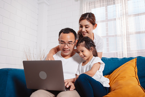 Family parents planing insurance to daughter by laptop computer searching assurance information at home.