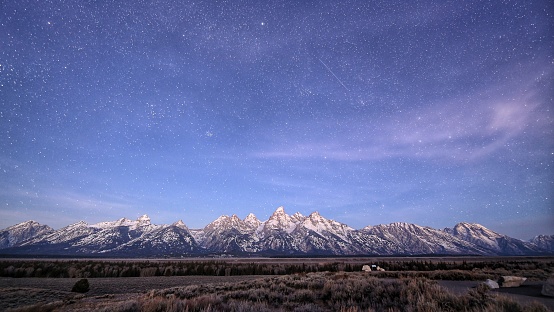 landscape photo of stars light over Grand Teton mountains in Grand Teton National Park . Long exposure photoshoot contained noise and grain