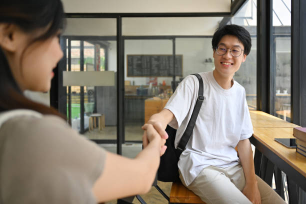 istock Smiling asian university student man shaking hands, greeting his friend. 1498093088