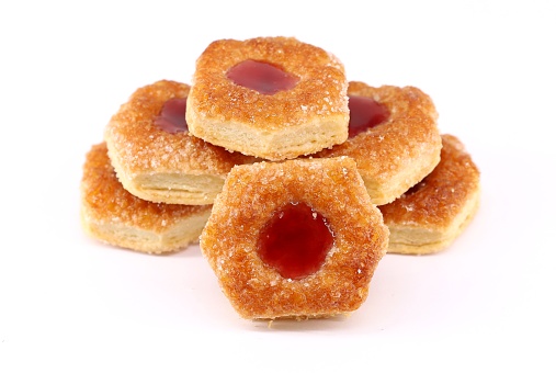 Group of small puff pastry cookies stuffed with berries jam on a white background.