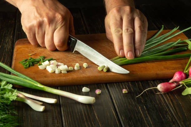istock Chef hands cut fresh onion leaves on cutting board for vitamin salad. Diet menu in preparation for dinner in the kitchen 1498098424