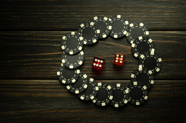 istock Playing craps or poker on a black vintage table. Chips and dice from a lucky win. Free black space for advertising 1498098601