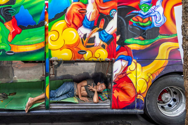 Bangkok, Thailand - March 28th 2023: Bus driver sleeping in the luggage compartment of his bus in the center of the capital of Thailand