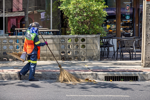Bangkok, Thailand - March 25th 2023: Street sweeper working with professional equipment  in the center of the capital of Thailand