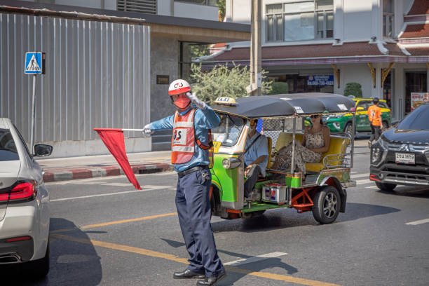 Bangkok, Thailand - March 24th 2023: Man with a red flag directing the traffic in a street in the center of the capital of Thailand