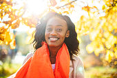 Young adult black woman portrait in red scarf at sunny weather in park