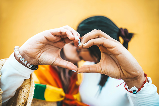 Lesbian couple making heart shape with fingers - Two girlfriends celebrating gay pride day together - Lgbt community and gender equality concept