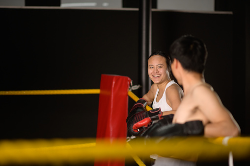 Female and Male Chinese Boxers taking a break chatting with boxing gloves in a gym in Cape Town, South Africa.