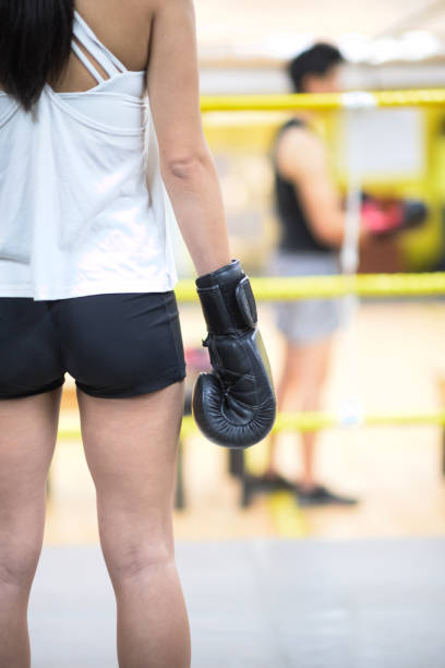 rear view part of female with boxing glove standing in boxing ring with male boxer standing defocused in background - short phrase business abstract business concepts business imagens e fotografias de stock