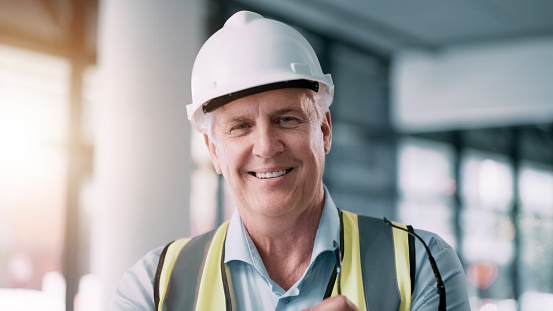 Architecture, construction and portrait of a contractor with smile at a site for building, engineering and maintenance on a house. Vision, development and senior construction worker at industrial job