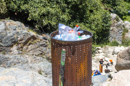 Recycling Bin in Ourika Valley at Atlas Mountains, Morocco, with cola bottle labels visible and people in the background.