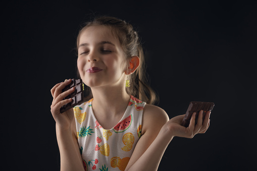 Chocolate and pretty hungry little woman portrait. Beautiful girl ready to eat chocolate bar.