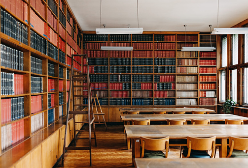 Photo of the university library interior.  There are desk with chairs in the middle part of the room