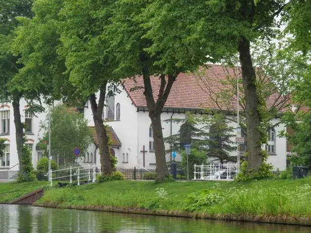 A picturesque scene featuring a building situated next to a body of water, with trees and a bridge on top