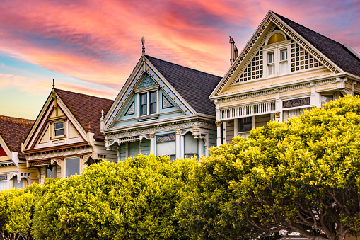 Photograph of the Painted Ladies of San Francisco in the state of California, USA. Californian Victorian houses of USA under an orange sky at sunset. Concept America.