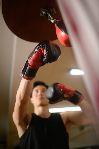 Directly below Male Chinese Speedball speed bag punching technique boxing in a gym in Cape Town South Africa