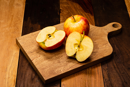 Front view of two fresh red apple fruit on cutting board, on wooden table in the kitchen at home.