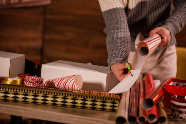 istock Man using scissors and cutting up wrapping paper around a Christmas gift box 1498109080