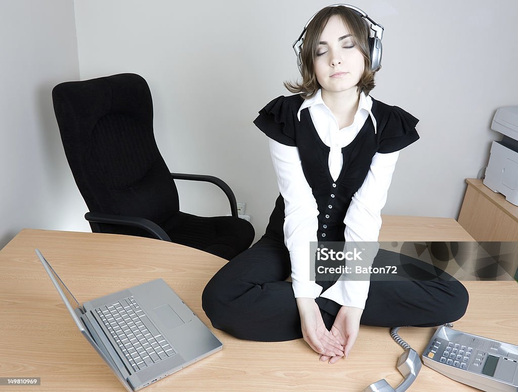 Young businesswoman sitting on the desk Young businesswoman sitting on the desk and listening to music Adult Stock Photo