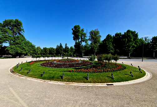 ornamental flowerbed in front of the castle on the ground floor. The planting of annuals is in the shape of a circle with a moon shape. tree roses, stars, c moon, beige threshing sand, broderie, elipse, oval\nscoop