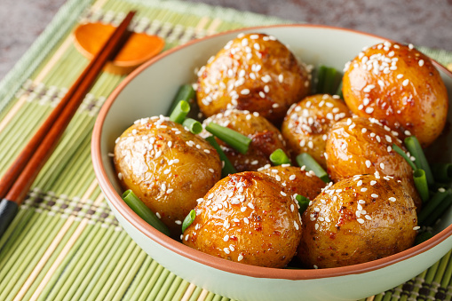 Korean Potato Side Dish Gamja Jorim braised in a sweet soy and sesame sauce closeup on the bowl on the table. Horizontal