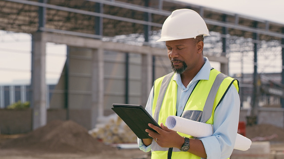 Man, construction and tablet at site for project management, building logistics or app. Male person and engineering worker on digital technology at industrial architecture design