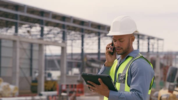 istock Man, construction and tablet with phone call at site for project management or building logistics. Male person and engineering worker talking on technology at industrial architecture design 1498116650