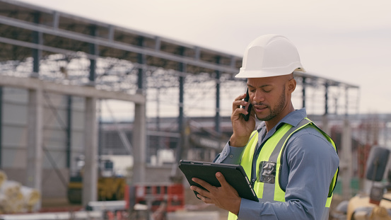 Man, construction and tablet with phone call at site for project management or building logistics. Male person and engineering worker talking on technology at industrial architecture design