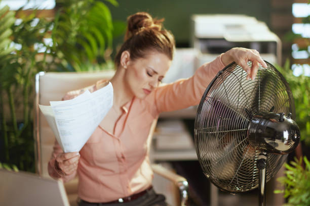 woman worker in green office suffer from heat stock photo