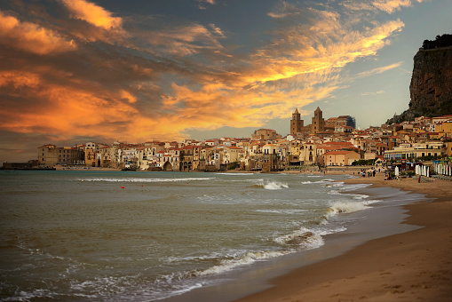 Sunrise in the beach of Cefalu with town in the background, Sicily, Italy