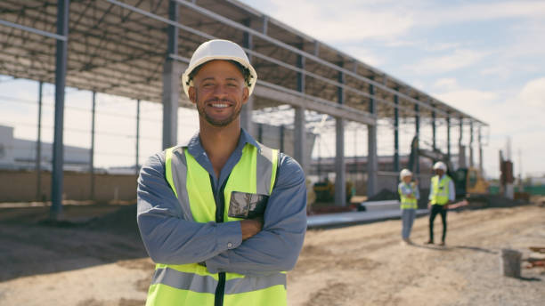 istock Happy man, construction and face with arms crossed for engineering, project management and labor. Portrait, smile and male builder at building site for property development or infrastructure 1498118359