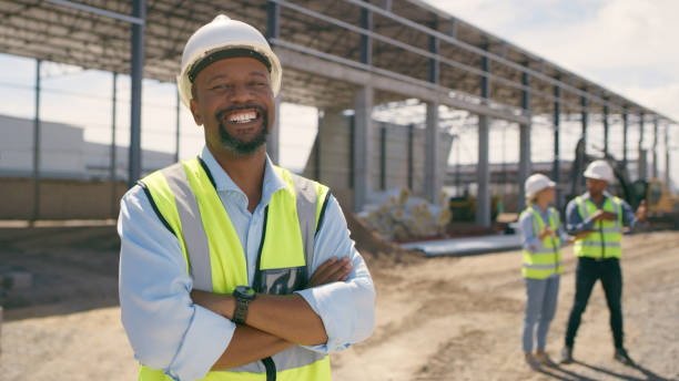 Happy man, construction and face with arms crossed for engineering, project management and labor. Portrait, smile and male builder at building site for property development or infrastructure