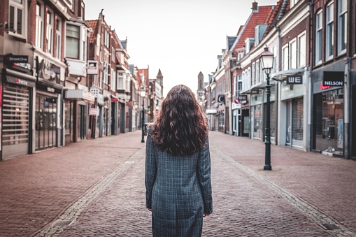 Hoorn, Netherlands – February 04, 2020: A female adult stands in the middle of a road, looking back with a contemplative expression