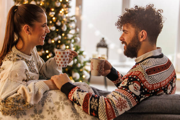 istock Young couple smiling at each other while relaxing and enjoying hot chocolates 1498120090